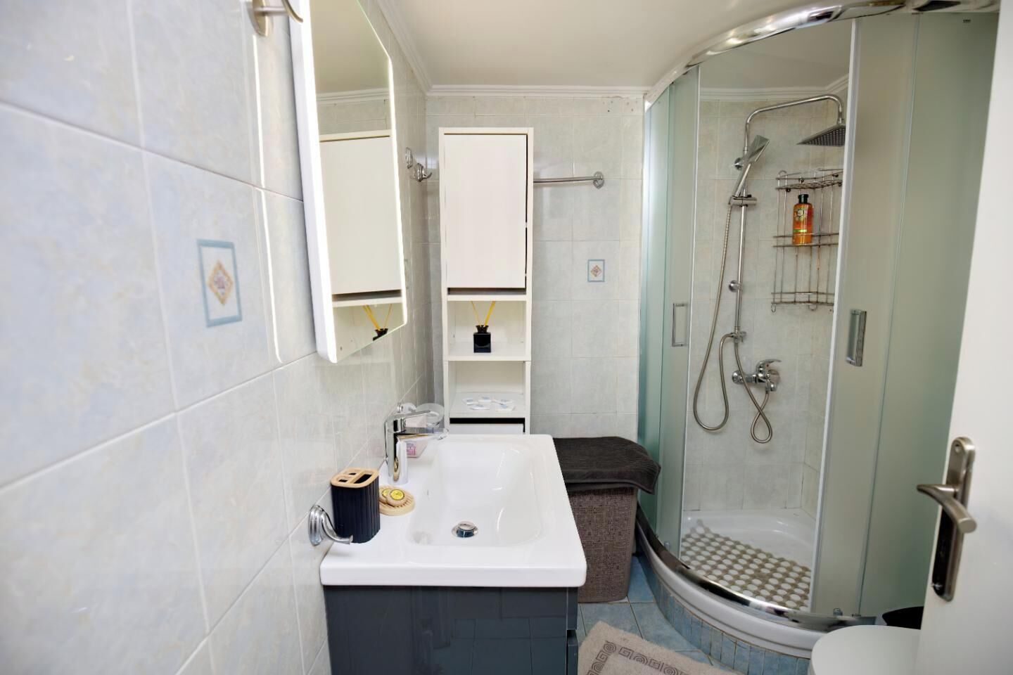 Une salle de bain avec un lavabo blanc, une cabine de douche en verre et un porte-serviettes.