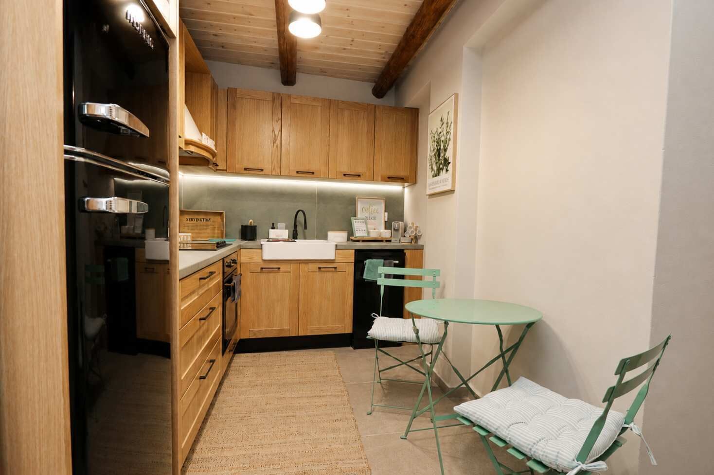 A compact kitchen with wooden cabinets, a sink, and a small dining area with a table and chairs.
