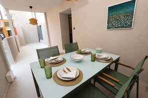 A dining area with a table set for four, chairs, and a painting on the wall. - A2 Maisonette - Modern Cretan Living by the Sea (Hersonissos)