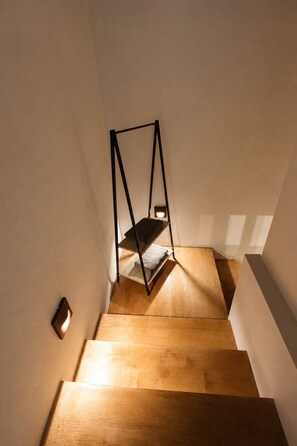 A wooden staircase with a minimalist design, a single light fixture on the wall, and a shadow cast by the structure. - A2 Maisonette - Modern Cretan Living by the Sea (Hersonissos)