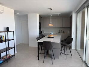 Eine moderne Küche mit Kochinsel, Barhocker und Bücherregal.