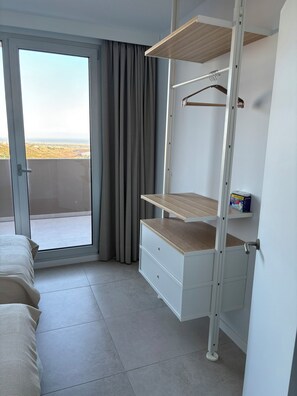 Une chambre dotée d’une armoire intégrée, d’une porte-fenêtre coulissante donnant sur un balcon et offrant une vue sur le paysage.