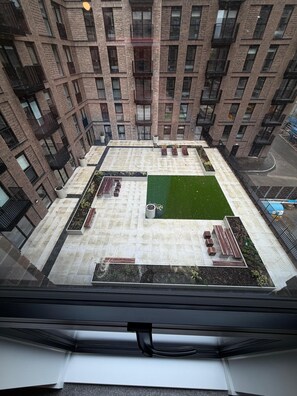 A high-rise building with a rooftop garden featuring seating areas and a small lawn. - Stunning 3 Bedroom Apartment-2 Bath with Balcony (Salford)