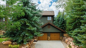 A residential house with a stone driveway, wooden garage doors, and a well-maintained garden with various plants and a rock border. - 6BR Deer Valley retreat with hot tub, game room, and mountain views. (Park City)