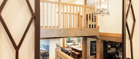 Een meerlaags interieur met een houten trap, een eetgedeelte en een bibliotheek.