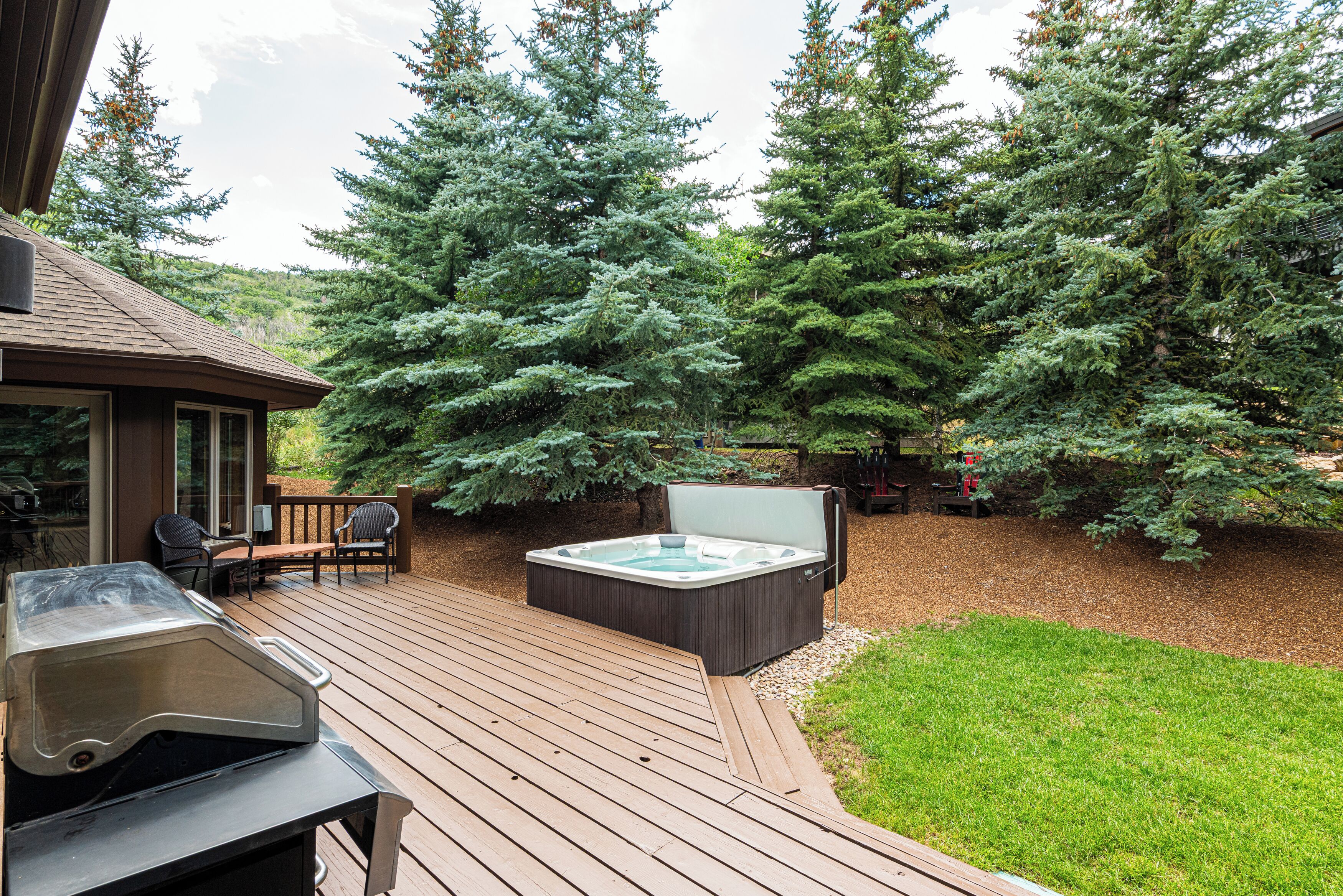 A deck with a hot tub, barbecue grill, and outdoor seating.