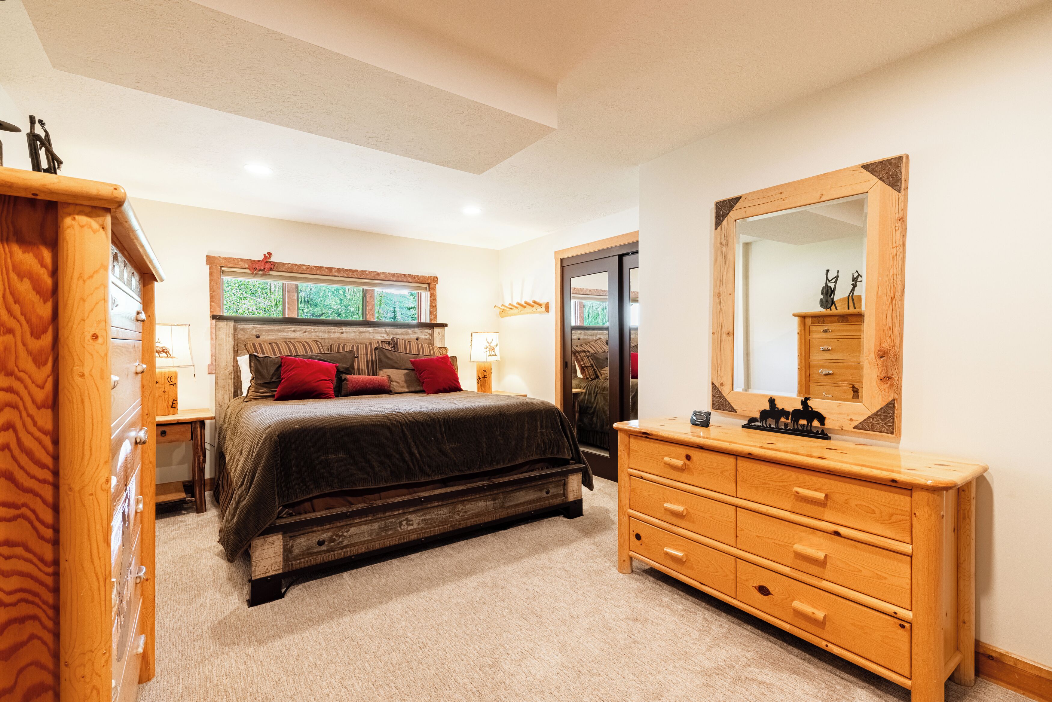 A bedroom with a large bed, wooden dresser, and a mirror.