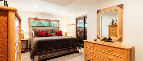 A bedroom with a large bed, wooden dresser, and a mirror.