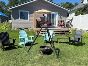 Ein Garten mit einer Terrasse, Sitzgelegenheiten im Freien und einer Feuerstelle.