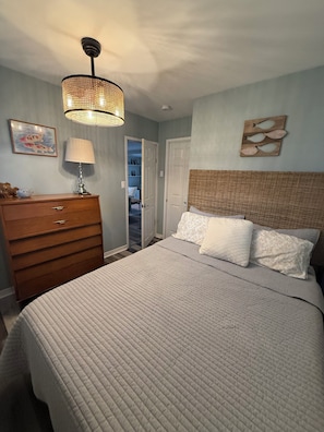 Ein Schlafzimmer mit Bett, Schminktisch, Lampe und einer Tür zu einem Schrank.