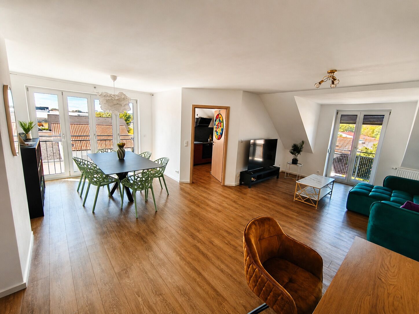 Un grand espace de vie comprenant une table à manger, des chaises, un canapé et un téléviseur.