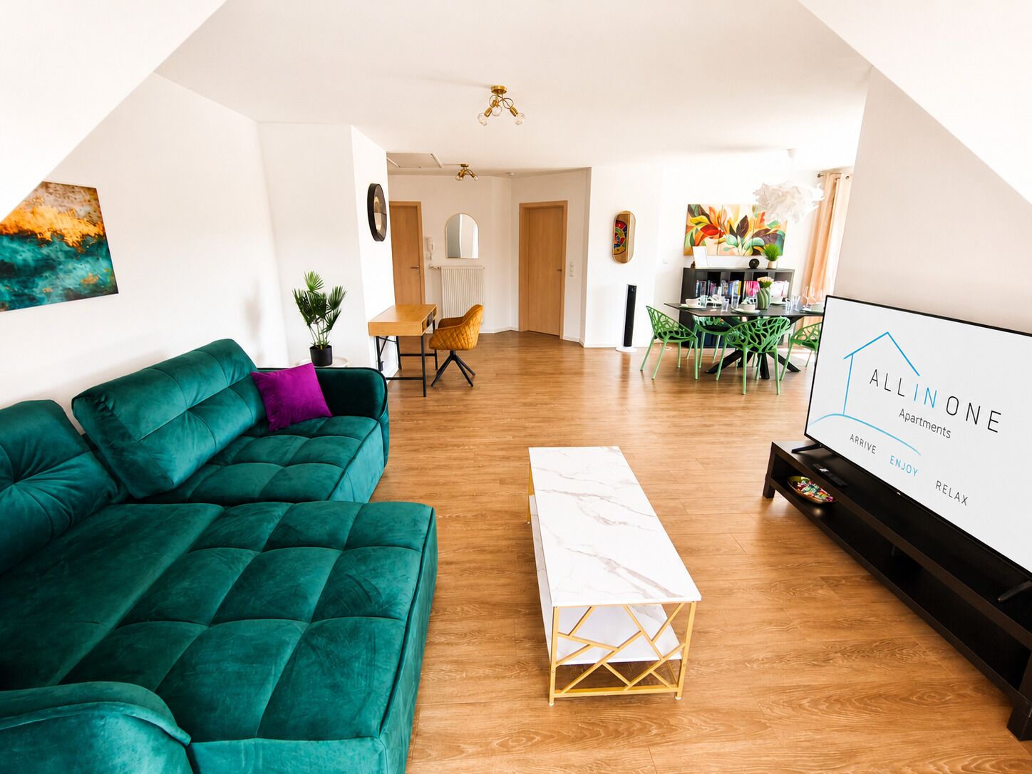 Un saló modern amb un sofà verd, una taula de cafè blanca i una televisió que mostra 'ALLINONE Apartments'.
