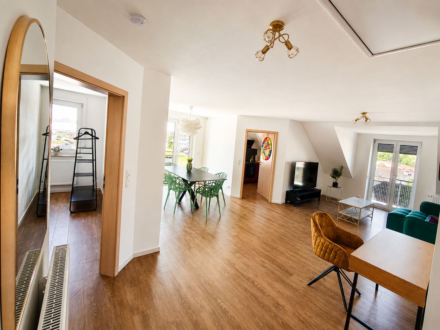 Ein geräumiger Wohnbereich mit Esstisch, Stühlen, Fernseher und einer Couch.