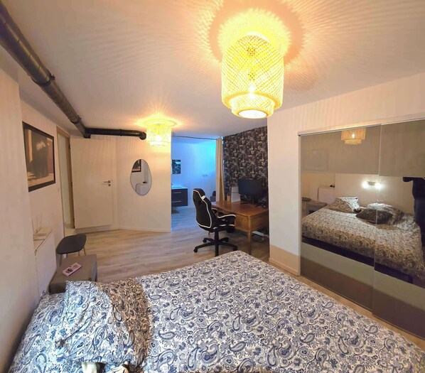 Un dormitorio con una cama grande, un escritorio, una silla y un espejo.