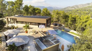 A modern villa with a swimming pool, outdoor seating, and a view of the surrounding landscape. - Villa Horizona in G Menos (Gemenos)