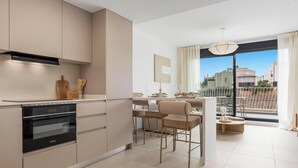 Et moderne køkken med indbyggede apparater, et spiseområde med udsigt og en balkon med gelænder.
