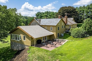 A two-story house with a patio area and a lawn.