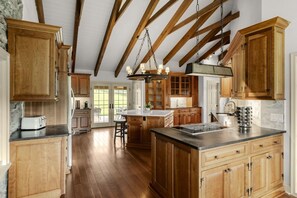 Une cuisine spacieuse avec des meubles en bois, un îlot central et un plafond voûté.