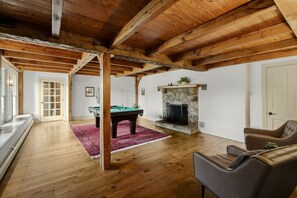 Ein geräumiger Raum mit Billardtisch, Kamin und Sitzecke.