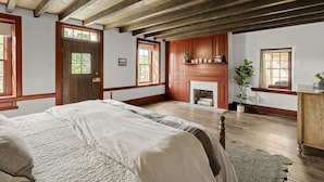 Un dormitorio con una cama grande, vigas de madera, una chimenea y un ventanal.