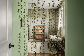 A room with a green wall, a wooden bookshelf, and a dining table with chairs.