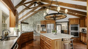 Una cocina amplia con una isla grande, armarios de madera y una pared decorativa de piedra.