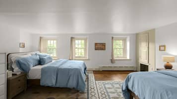 A bedroom with two beds, a nightstand, a dresser, a window with curtains, a radiator, and a lamp.