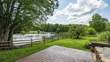 A brick patio with a view of a lake and a wooden fence.
