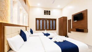 A hotel room with a large bed, a wardrobe, a television, and a ceiling fan. - Hotel Char Dham Inn - Varanasi (Varanasi)