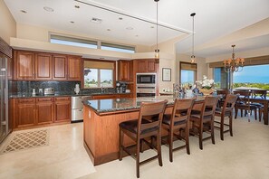 Una cocina amplia con gabinetes de madera, encimeras de granito y una isla central con sillas.