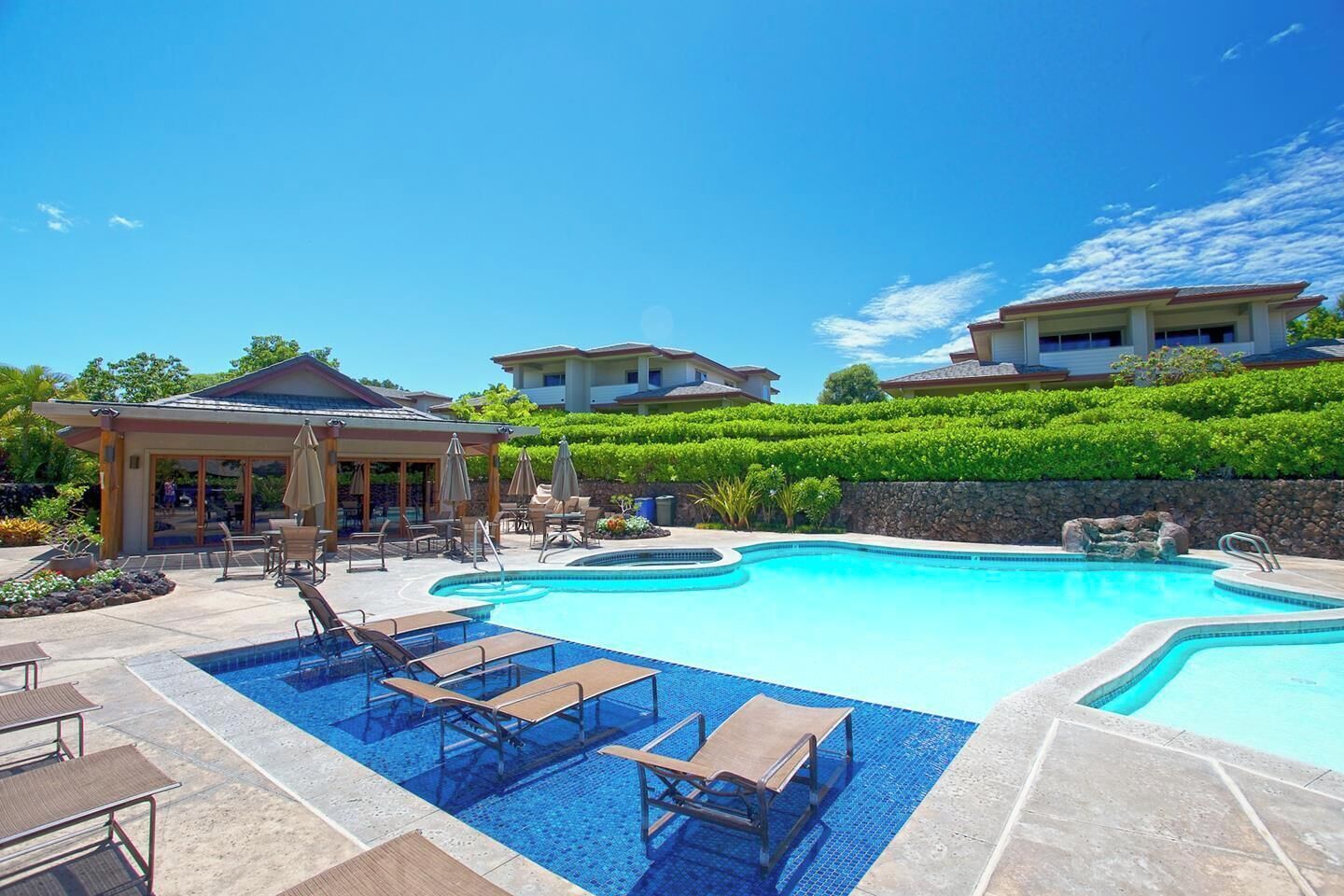 Un resort con una piscina grande, sillas de descanso y un área de patio techada.