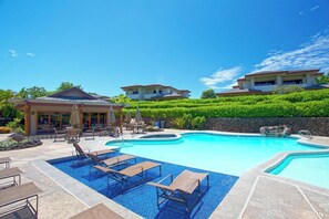Ein Resort mit großem Schwimmbecken, Liegestühlen und einer überdachten Terrasse.