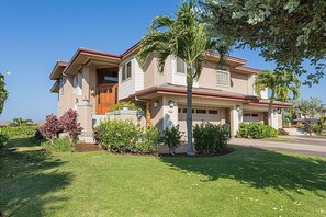 Ein zweistöckiges Haus mit rotem Dach, einer Veranda und einem gepflegten Rasen.