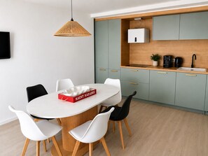 Une cuisine moderne avec des meubles de couleur vert clair, un plan de travail blanc et une cuisinière intégrée.