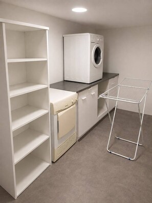A laundry room with a washing machine, dryer, and a drying rack. - Villa Océa 1900 face mer, terrasse panoramique (Saint-Nazaire)