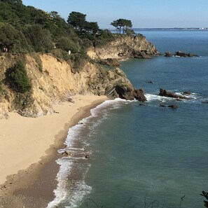 Un paysage côtier avec une plage de sable, des falaises rocheuses et une vue dégagée sur la mer.