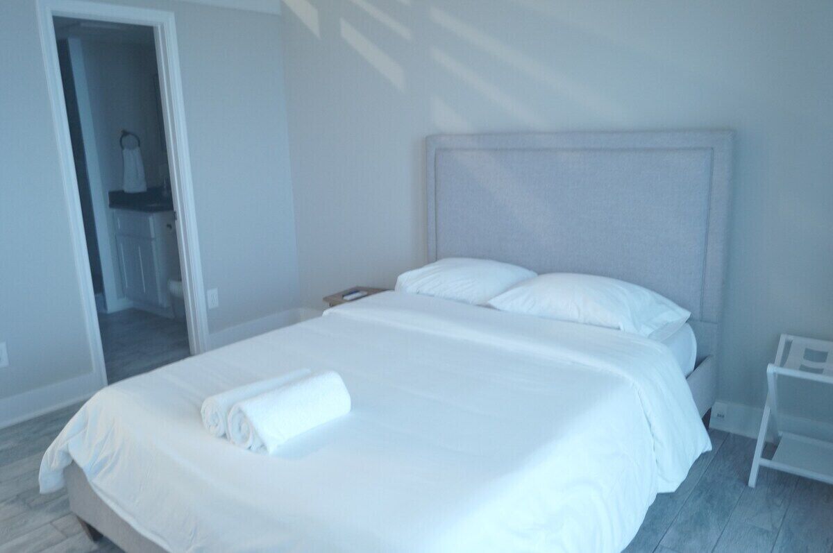 A hotel room with a large bed, a bedside table, and a door leading to a bathroom.