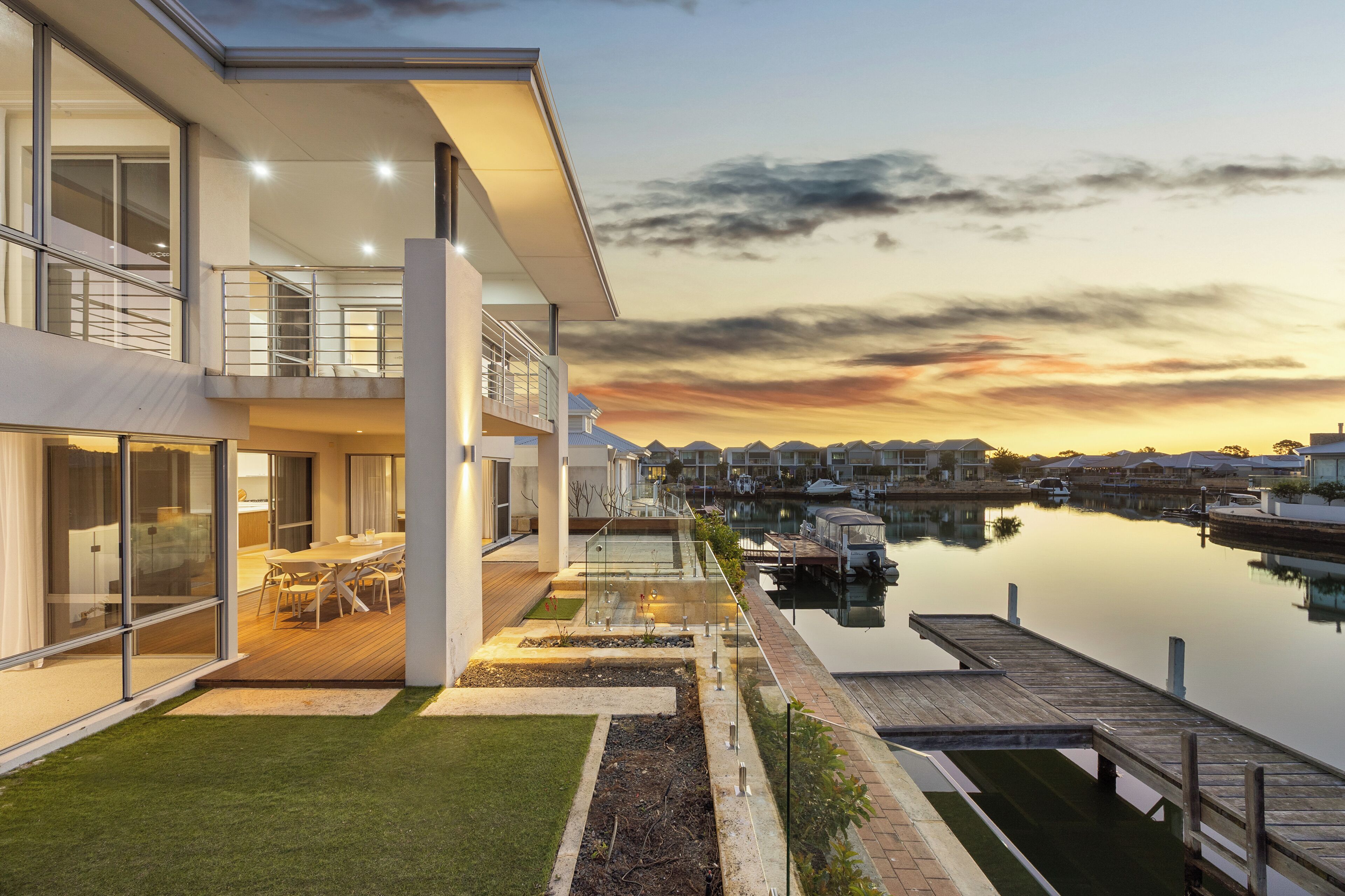 Une maison moderne à deux étages dotée d’un balcon en verre donnant sur une marina.