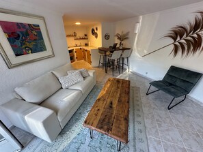 A living room with a sofa, a wooden coffee table, and a black chair. There is a dining area with a table and chairs in the background. - Villa Helios - Within walking distance of Moraira - plenty of space and privacy (Teulada)