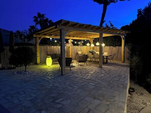 Ein Außenbereich mit Terrasse, einer Pergola, Sitzgelegenheiten und Lichterketten.