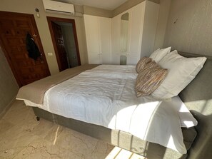 Ein Schlafzimmer mit einem Bett, einer Holztür, einer Klimaanlage und einem Spiegel.