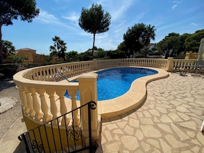 A swimming pool with a curved edge, surrounded by a stone-tiled deck and a balustrade. - Villa Helios—Private Pool—Walking Distance to Moraira Center—Plenty of Space and Privacy (Teulada)