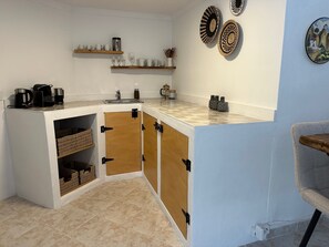 A compact kitchen with a built-in island, a sink, and storage cabinets. - Villa Helios - Within walking distance of Moraira - plenty of space and privacy (Teulada)