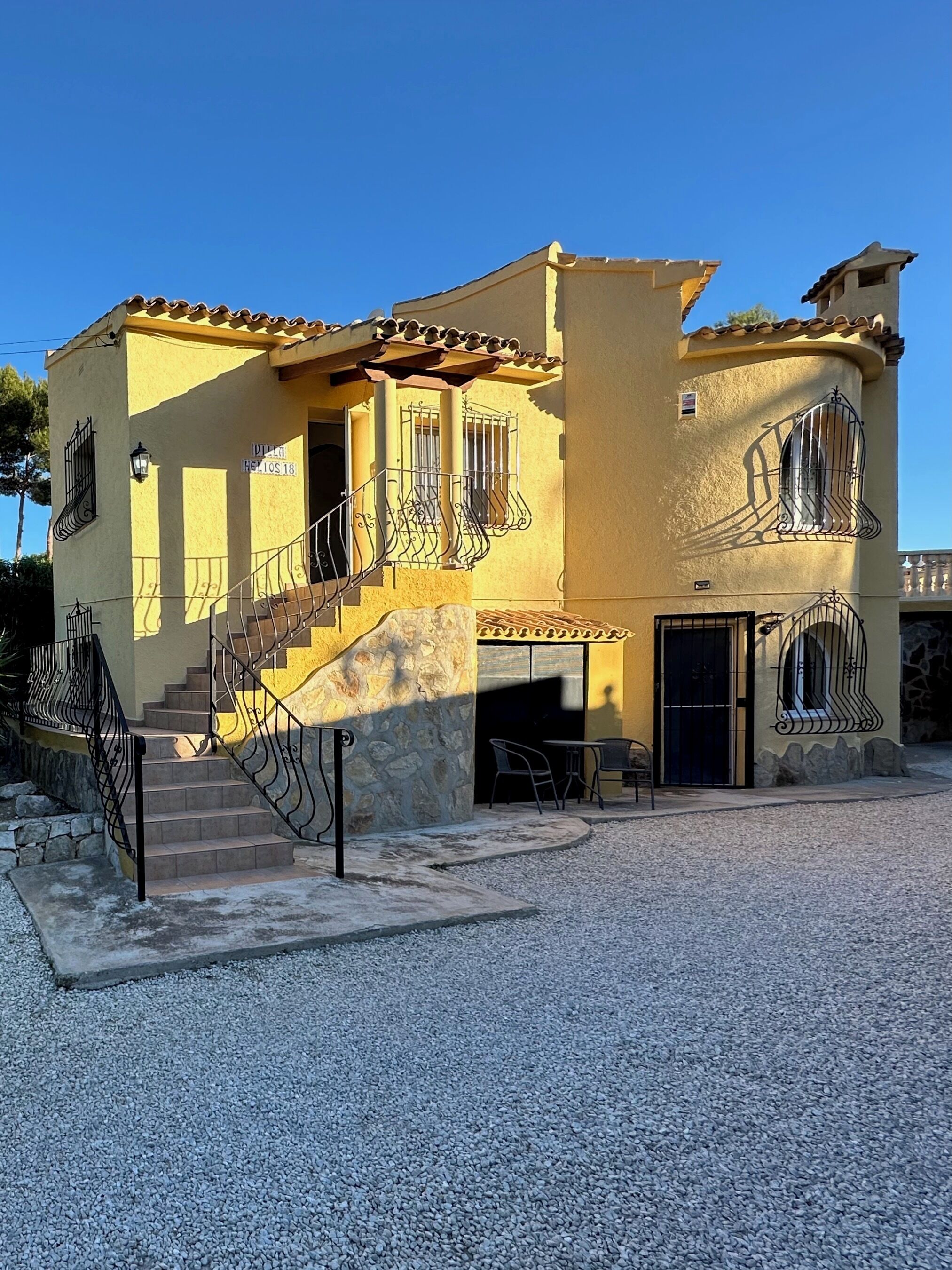 A two-story building with a stone staircase, a balcony, and a door with a metal gate.