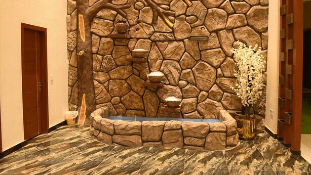 A stone wall with a built-in hot tub, a wooden door, and a vase with flowers. - Hard Rock Hotel (Islamabad)
