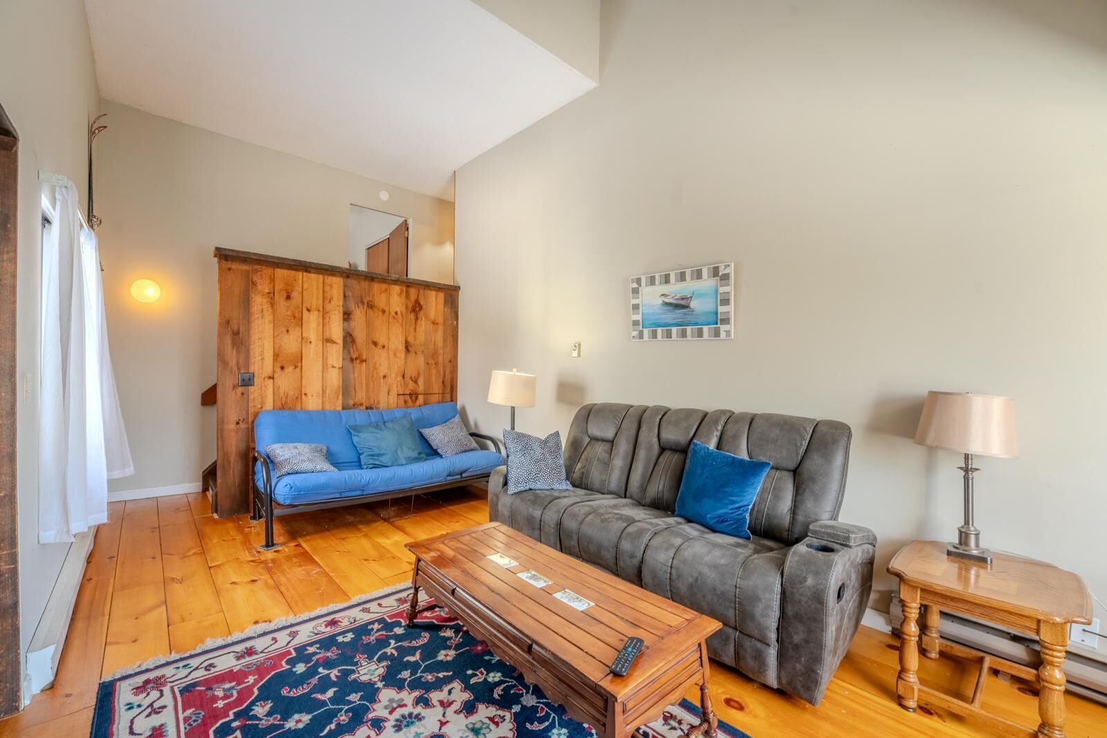 A living room with a blue sofa, a grey sofa, a wooden coffee table, and a small wooden side table.