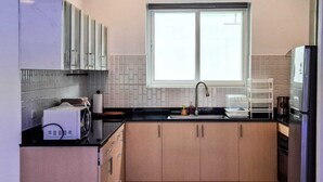 Eine kleine Küche mit Fenster, Mikrowelle, Spüle und Schränken.