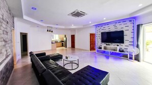 Ein modernes Wohnzimmer mit einer Eckcouch, einem Couchtisch und einem Flachbildfernseher, der an einer Wand mit geometrischem Muster angebracht ist.