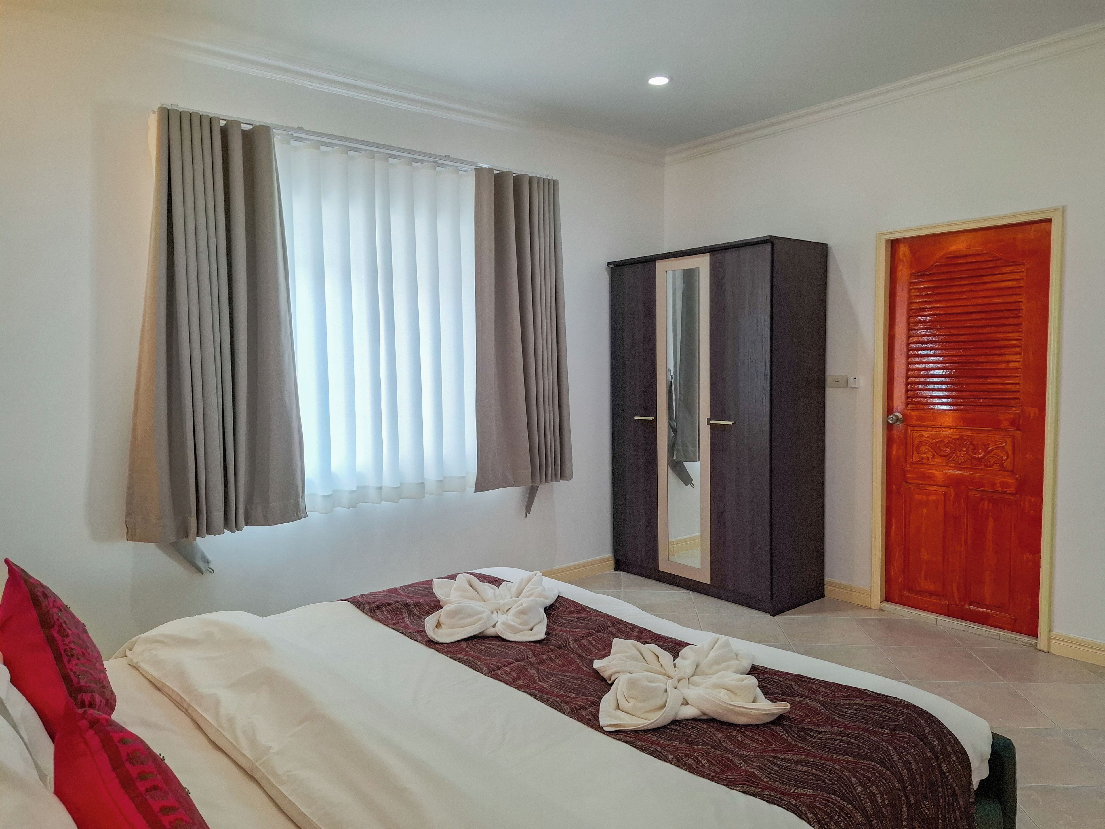 A hotel room with a bed, a wardrobe, and a door.
