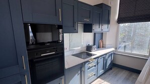 Una cucina moderna con mobili scuri, forno integrato e una finestra con vista.